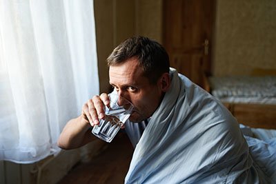 Состояние похмелья Мужчина пьет воду из стакана