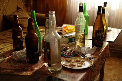 Алкогольное застолье Пустые бутылки с алкоголем на столе