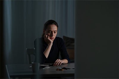 Депрессия Девушка сидит за столом и смотрит грустно вниз