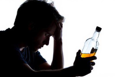 Расстроенный мужчина с бутылкой алкоголя в руках