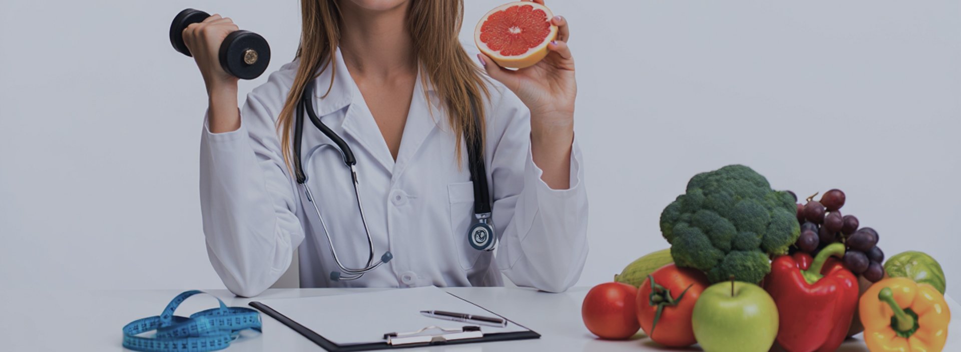 Девушка доктор рядом с фруктами и овощами, в руках у нее гантеля